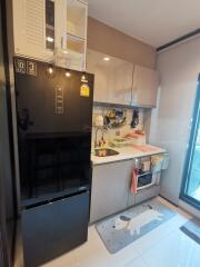 Modern compact kitchen with black refrigerator, sink, cabinetry, and glass sliding door