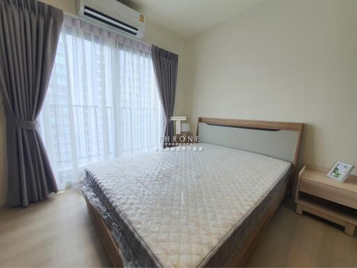 A modern bedroom with a large window, bed, air conditioner, and a nightstand