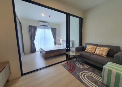 Modern living room with view into bedroom through glass sliding doors