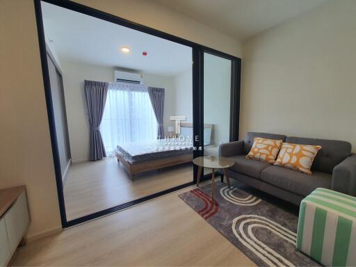 Modern living room with view into bedroom through glass sliding doors