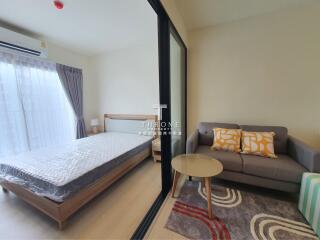 Bedroom view with a bed, sofa, table, and large sliding glass door