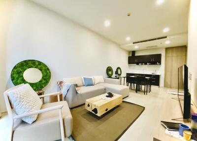 Modern living room with couch, coffee table, TV, and open kitchen