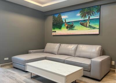 Modern living room with a gray sectional sofa and a tropical painting