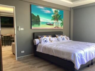 Bedroom with a large bed, tropical wall art, and adjacent living space