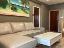 Comfortable living room with beige leather sofa and a tropical-themed painting above it, white coffee table