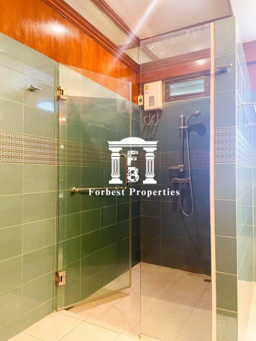 Well-lit bathroom with green tiled walls and glass shower enclosure