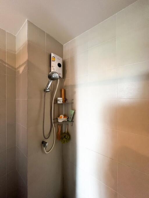 Shower area with tiled walls and storage shelf