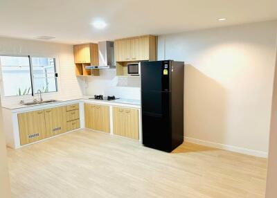 Modern kitchen with wooden cabinets and black refrigerator