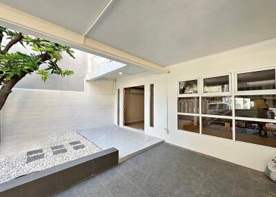 Modern covered patio adjacent to house with pebble garden feature