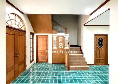 Spacious foyer with green tiled floor and wooden staircase