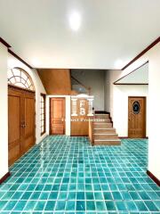 Spacious foyer with green tiled floor and wooden staircase