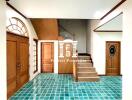 Spacious foyer with green tiled floor and wooden staircase