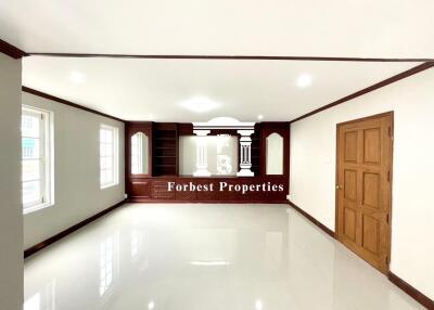 Spacious main living area with glossy white tile flooring and wooden accents