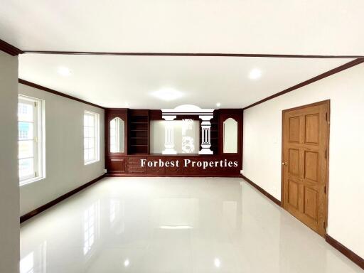 Spacious main living area with glossy white tile flooring and wooden accents