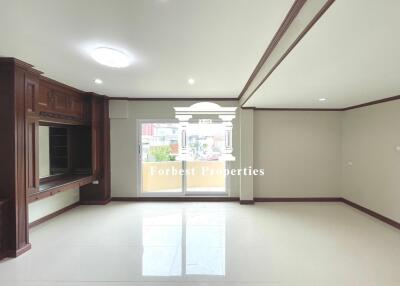 Spacious living room with large windows and built-in wooden cabinets