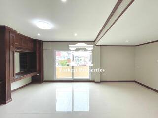 Spacious living room with large windows and built-in wooden cabinets