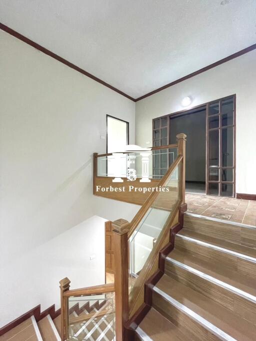 Staircase with wooden railing and glass panels in a modern interior