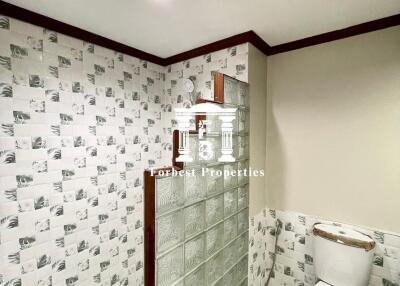 Bathroom with tiled walls and glass block divider