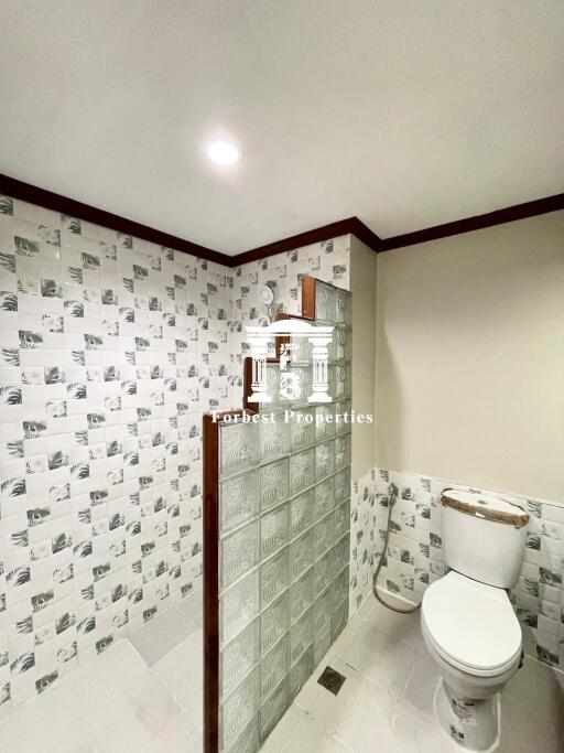 Bathroom with tiled walls and glass block divider