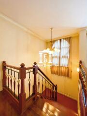 Staircase with wooden rails and chandelier