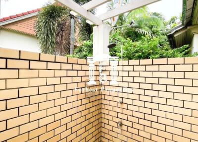 Outdoor shower area with brick walls and a pergola roof