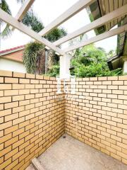 Outdoor shower area with brick walls and a pergola roof