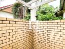 Outdoor shower area with brick walls and a pergola roof