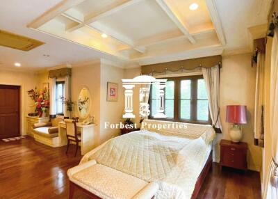 Spacious bedroom with wooden flooring, large windows, and a high ceiling