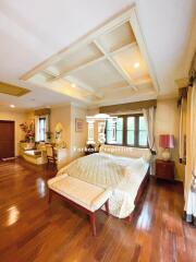 Spacious bedroom with wooden flooring, large windows, and a high ceiling