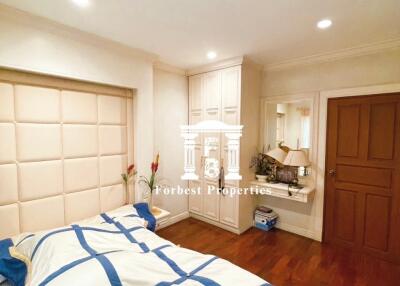 A cozy bedroom with wooden floor, built-in wardrobe, and a well-decorated bed.