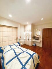 A cozy bedroom with wooden floor, built-in wardrobe, and a well-decorated bed.