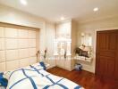 A cozy bedroom with wooden floor, built-in wardrobe, and a well-decorated bed.