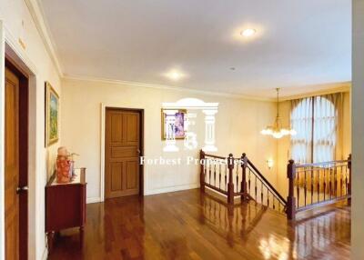 Spacious hallway with wooden flooring, stairway, and lighting