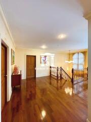 Spacious hallway with wooden flooring, stairway, and lighting