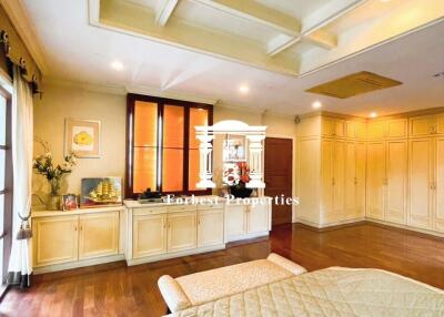 Spacious and well-lit bedroom with wooden flooring, coffered ceiling, and large windows