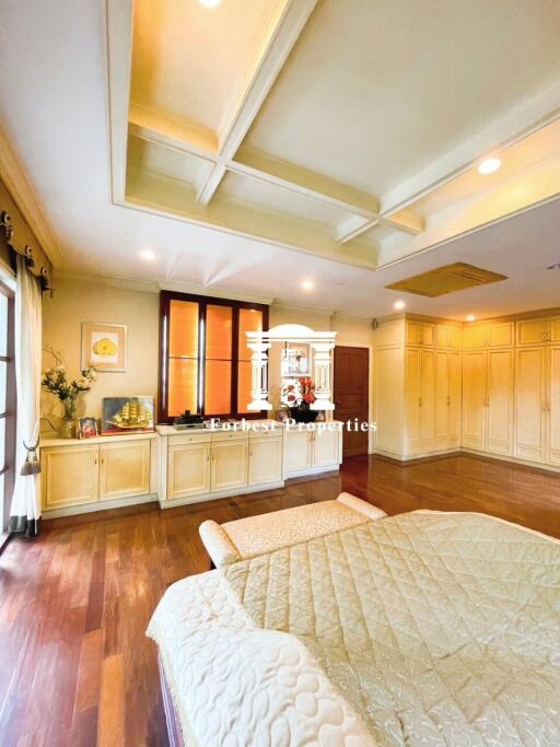 Spacious and well-lit bedroom with wooden flooring, coffered ceiling, and large windows