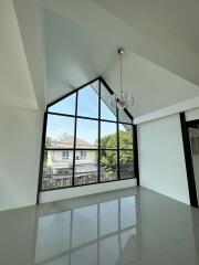 Spacious living room with large triangular window and chandelier