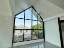 Spacious living room with large triangular window and chandelier