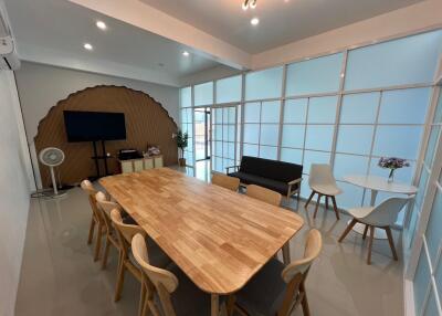 Modern meeting room with a wooden table, chairs, and multimedia setup