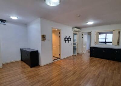 Spacious living room with wooden flooring, white walls, and ample lighting