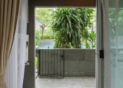 View from inside the room with a sliding door open to a patio and garden area