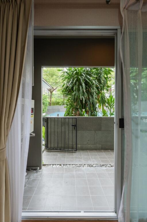 View from inside the room with a sliding door open to a patio and garden area