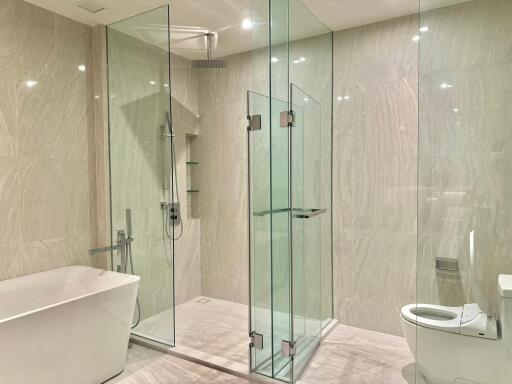 Modern bathroom with glass-enclosed shower, bathtub, and toilet