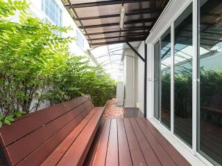 Outdoor patio area with wooden benches and greenery