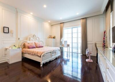 Spacious elegant bedroom with large bed, hardwood floors, and large windows