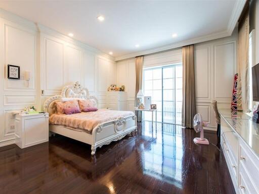 Spacious elegant bedroom with large bed, hardwood floors, and large windows