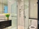 Modern bathroom with glass shower, vanity, and toilet