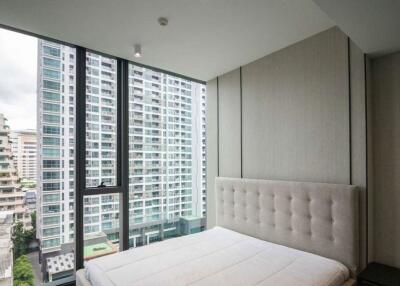 Modern bedroom with large windows overlooking high-rise buildings