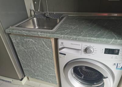 Compact kitchen area with stainless steel sink and washing machine