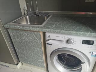 Compact kitchen area with stainless steel sink and washing machine